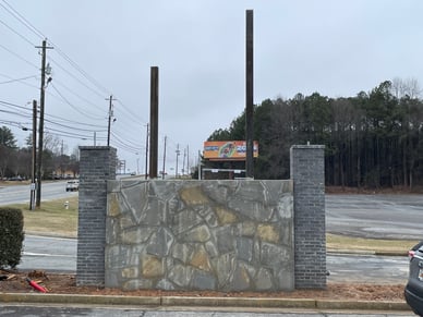 Custom monument sign with brick pillars and stone veneer base in Metro Atlanta, featuring tall vertical posts for commercial property identification