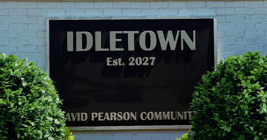 Black routed HDU neighborhood sign for Idletown by David Pearson Communities, installed on a brick wall.