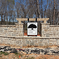 “Neighborhood entrance hanging monument sign set in a stone wall, custom fabricated by Marietta Signs in Metro Atlanta